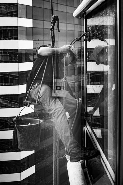 Une femme adulte en combinaison rouge utilise un aspirateur dans un intérieur moderne, concentrée sur des tâches de nettoyage.